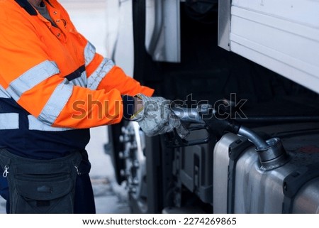 Man refueling diesel on big rig truck, truck driver refueling, global warming, pollution, fossil fuel, Royalty-Free Stock Photo #2274269865