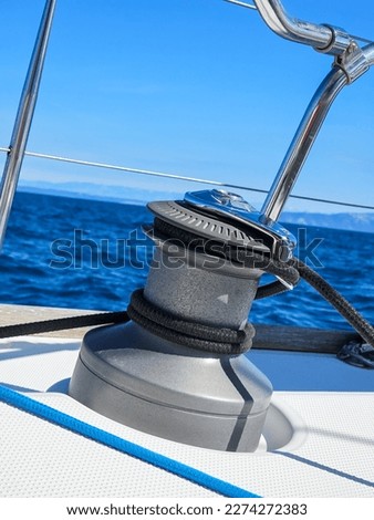 Winch on a sailing boat with black rope against blue sea while sailing Royalty-Free Stock Photo #2274272383
