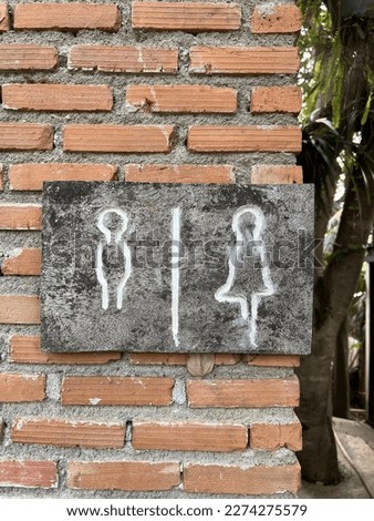 Wooden restroom sign on brick wall