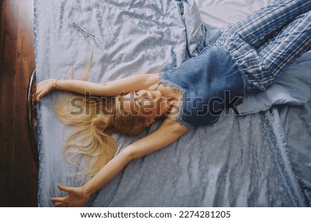 Mature middle aged woman stretching in bed waking up alone