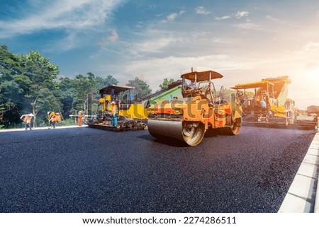 Construction site is laying new asphalt pavement, road construction workers and road construction machinery scene. Highway construction site scene. Royalty-Free Stock Photo #2274286511