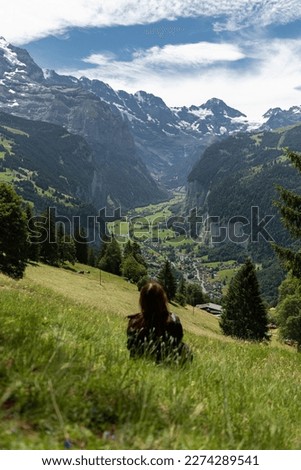 Woman Sitting In The Meadow Looking At Lauterbrunnen Valley