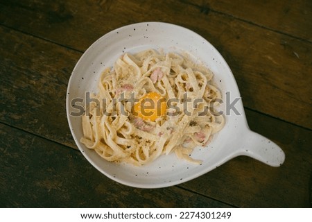 pasta carbonara on a plate with egg yolk and bacon and cheese