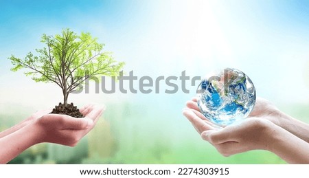 Two human hands holding the earth and trees in heart shape on blurred nature background. Elements of this image furnished by NASA