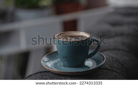 Blue cup of coffee on the grey sofa with lighting background.