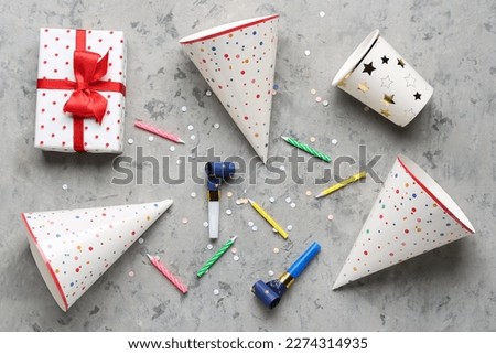 Composition with party hats, whistles, candles and gift box on grunge background