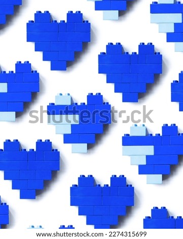 Blue hearts from toy blocks isolated on white background, minimal geometric pattern from bricks, shapes heart from child construction. Wallpaper of plastic blocks, top view repeat pattern