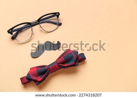 Composition with eyeglasses, paper mustache and bow tie on color background