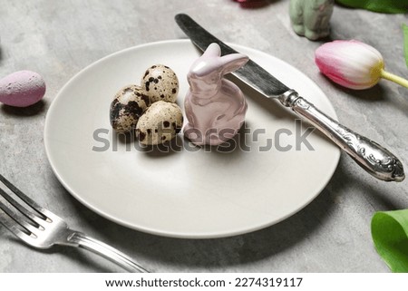 Table setting with Easter rabbit and quail eggs on grunge background, closeup