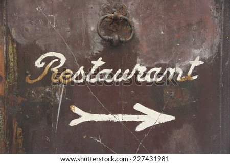 Old brown door with signature restaurant and arrow as Background