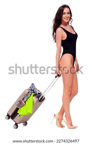 Full length portrait of a beautiful young woman in black swimsuit with suitcase, isolated on white background