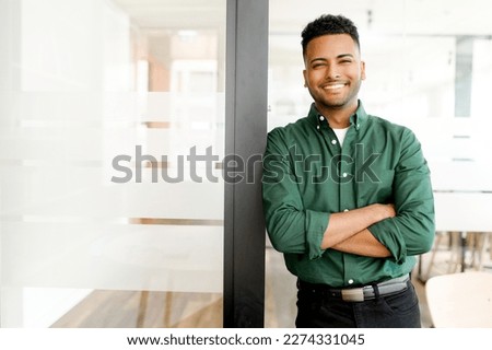 Successful indian authoritative confident young brunet adult male entrepreneur businessman professional in smart casual wear standing with arms crossed at the modern office, looking at the camera Royalty-Free Stock Photo #2274331045