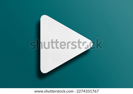 White paper cut into triangle shape, play button set on green paper background. Royalty-Free Stock Photo #2274331767