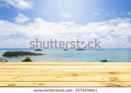 Empty wooden tables by the beach, with a blurred background of the sea, sky and clouds, copy space for text.