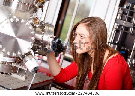 Female scientist looking to the laser deposition chamber Royalty-Free Stock Photo #227434336