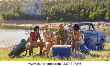 Group Of Friends With Backpacks By Pick Up Truck On Road Trip Drinking Beer From Cooler By Lake Royalty-Free Stock Photo #2274347245
