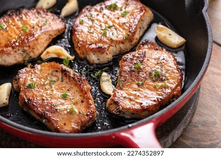 Pork chops cooked with garlic in a cast iron pan Royalty-Free Stock Photo #2274352897