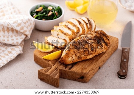 Grilled chicken breast with spice rub and lemon on a cutting board, sliced and whole Royalty-Free Stock Photo #2274353069