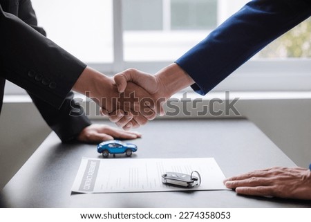 Two businessmen shaking hands to end a meeting Mature man signing a contract in the showroom office. trading ideas business partner.