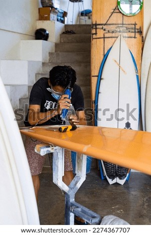 Craftsman surfboard Shaper working in a repair workshop