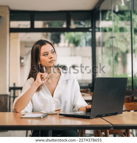 Vertical portrait developing a new business strategy. Young Caucasian business woman in formal clothes thinking about something and looking at laptop while sitting in modern office Royalty-Free Stock Photo #2274378655