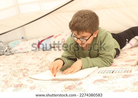 Earthquake survivor boy drawing in tent.