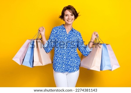 Photo cheerful positive woman dressed blue blouse rising shopping bargains isolated yellow color background