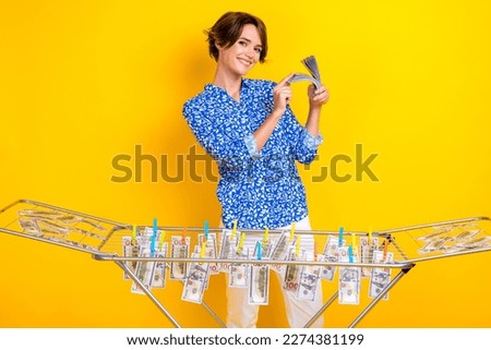 Photo of cheerful positive woman dressed blue blouse washing hanging cash rope isolated yellow color background