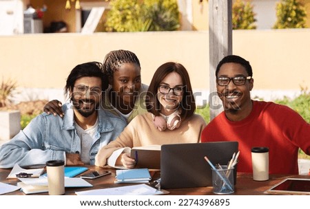 Happy millennial different people students studying with laptop together, working on project remotely outdoor. Modern education with device, group lesson, prepare to exam in college Royalty-Free Stock Photo #2274396895