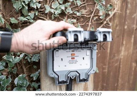 Homeowner showing a fully opened, double gang electrical socket and combined circuit breaker. Note the rubber casket giving a weatherproof seal to these outdoor electrical connections. Royalty-Free Stock Photo #2274397837