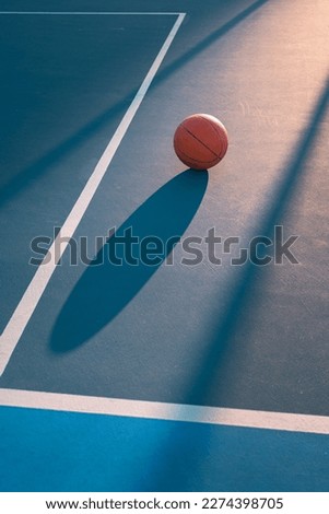 Detail of a ball on a basketball court at sunset. Set of lights, shadows and lines