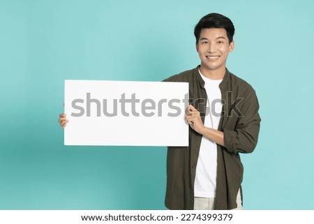 Asian man showing and holding blank white billboard isolated on green background