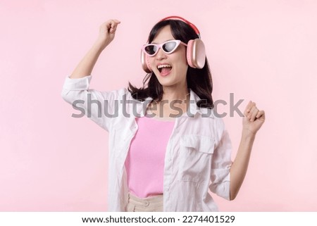 young happy asian woman model with stylish trendy sun glasses enjoy listening music by headphone audio and dancing isolated on pink studio background. technology, girl fashion, accessory concept.