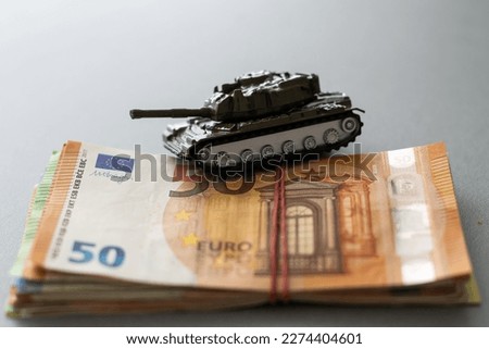 Economic crisis concept. Toy military tank on euro banknotes. War conflict in Ukraine, economic sanctions and inflation Royalty-Free Stock Photo #2274404601