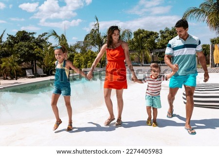 Happy biracial family walking and holding hands by the swimming pool. Spending quality time, lifestyle, family, summertime and vacation concept. Royalty-Free Stock Photo #2274405983