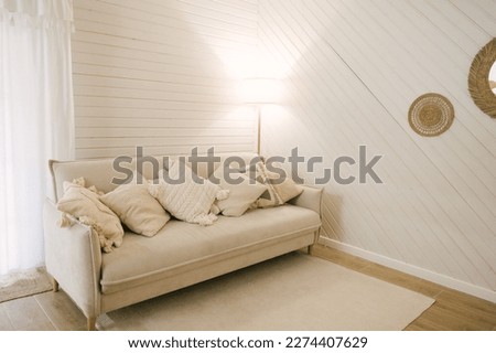 modern wooden house. Beautiful boho Scandinavian-style interior with a light sofa and fringed pillows Royalty-Free Stock Photo #2274407629