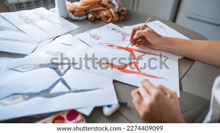 Faceless woman draws watercolor sketches of sportswear. Close-up of the hands of a fashion designer.