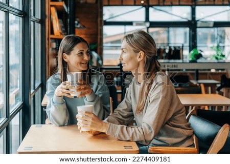 Two women sitting in a coffee house talking and drinking coffee. Royalty-Free Stock Photo #2274409181