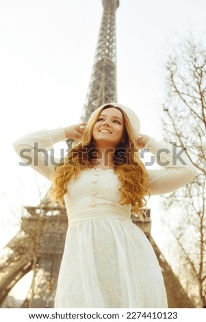An incredibly beautiful girl in a long white dress and a beret against the background of the Eiffel Tower. Fashion in Paris, travel and weddings. Romance in the city of love, a woman smiles.
