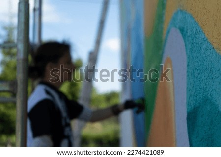 young blurred person painting a colorful graffito on a wall Royalty-Free Stock Photo #2274421089