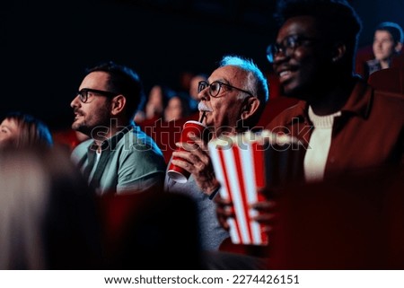 A group of multiethnic and multigenerational people are in the movie theater enjoying a movie on the big screen. Royalty-Free Stock Photo #2274426151