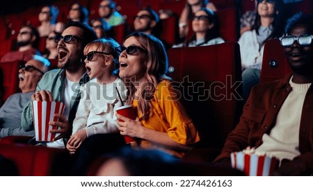 A young Caucasian family is in the cinema watching a 3D movie with 3D glasses and having fun. Royalty-Free Stock Photo #2274426163