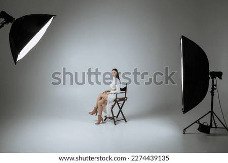 A girl in white clothes on a gray background of a photo studio