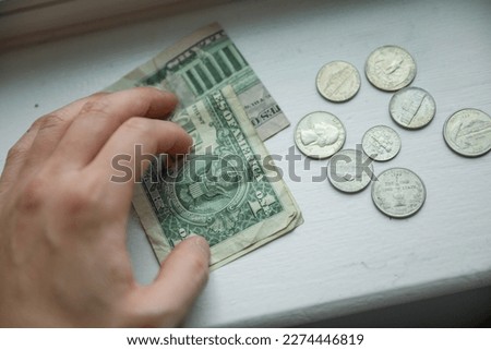 dollar and coins with hand showing the current finance and economy of the us market including the banks depicting savings and loans and the financial struggle to invest and success  Royalty-Free Stock Photo #2274446819