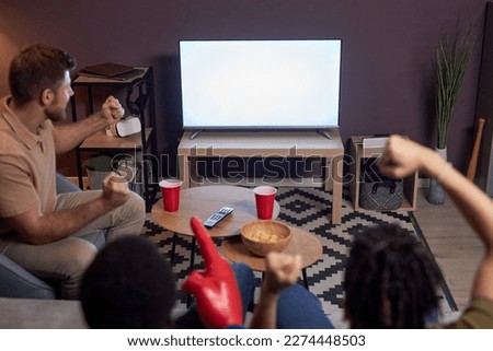 Group of emotional sports fans watching match on TV with blank screen mockup Royalty-Free Stock Photo #2274448503