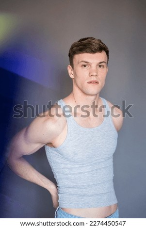 Young man with short hair and grey undershirt tank top