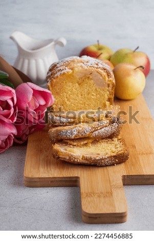 Blurred image of a cupcake with apples on a wooden board, apples and a bouquet of flowers.