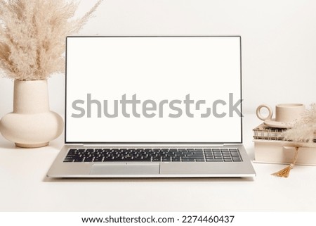 Mockup laptop with white screen on the table with vase, pampas grass and decorations. Aesthetic background for study, cozy home office, promotion, social media
