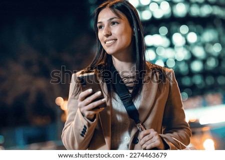 Shot of beautiful young woman using her mobile phone at night.