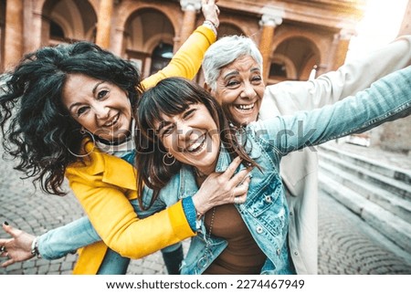 Three female best friends having fun together walking on city street - Happy mature women smiling at camera outside - Friendship concept with aged people hanging out on a sunny day - Backlight filter Royalty-Free Stock Photo #2274467949